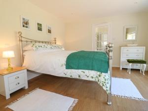 una camera da letto con un grande letto e un piumone verde di Wheelwrights Cottage a Grantham Altre 13 foto