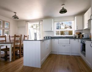a kitchen with white cabinets and a table and a dining room at Castaway in Port Isaac