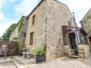 un antiguo edificio de piedra con una mesa y sillas al aire libre en Sandholme Cottage, en Skipton