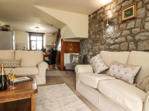 una sala de estar con sofás y una pared de piedra. en Sandholme Cottage, en Skipton