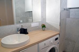 a bathroom with a sink and a washing machine at Maya's Flats & Resorts 52 - Aura 40 in Gdańsk