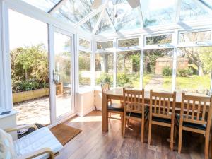 a conservatory with a table and chairs and windows at Flintstone Cottage in Norwich