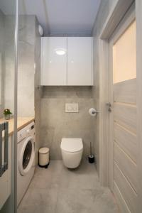 a bathroom with a toilet and a washing machine at Maya's Flats & Resorts 52 - Aura 40 in Gdańsk