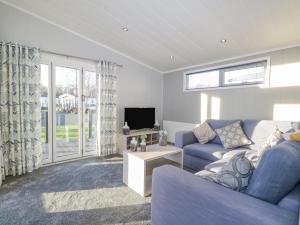 a living room with a blue couch and a tv at Yealand 36 in Carnforth