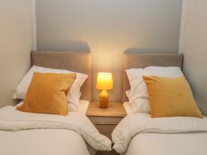 two beds in a room with a lamp on a night stand at Yealand 36 in Carnforth +18 photos