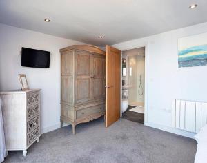 a bedroom with a wooden cabinet and a television at The Crows Nest in Port Isaac