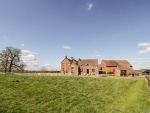 an old farm house with a fence in a field at Manor Farm Cottage in Worcester