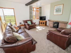 a living room with leather furniture and a fireplace at Manor Farm Cottage in Worcester