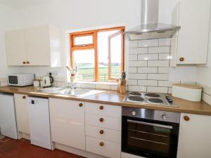 a kitchen with white cabinets and a sink and a window at Manor Farm Cottage in Worcester