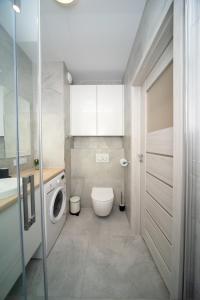 a bathroom with a toilet and a washing machine at Maya's Flats & Resorts 52 - Aura 40 in Gdańsk