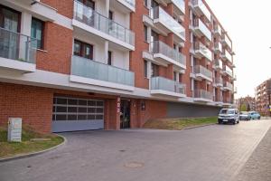 a red brick building with a car parked in the driveway at Maya's Flats & Resorts 52 - Aura 40 in Gdańsk