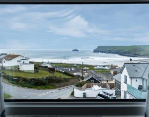 a view from a window of a town with the ocean at Pinewood 14 in Polzeath