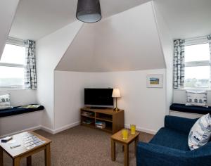 a living room with a blue couch and a tv at Pinewood 14 in Polzeath