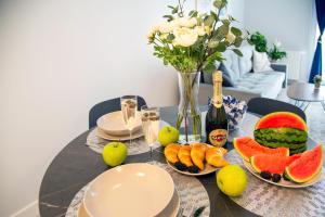 a table with a bunch of fruits and bottles of champagne at Maya's Flats & Resorts 52 - Aura 40 in Gdańsk