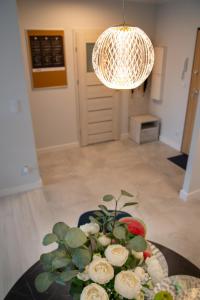 a table with a bowl of flowers and a chandelier at Maya's Flats & Resorts 52 - Aura 40 in Gdańsk