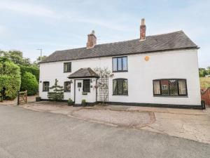 a white house with black windows and a driveway at The White Cottage in Burton upon Trent