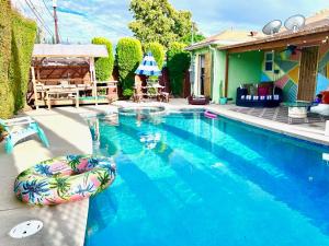 a swimming pool with a swimming float next to a house at Endless summer in LA *HEATED POOL/HOT TUB/CABANA* in Los Angeles