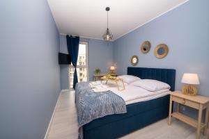 a blue bedroom with a bed and a table at Maya's Flats & Resorts 52 - Aura 40 in Gdańsk