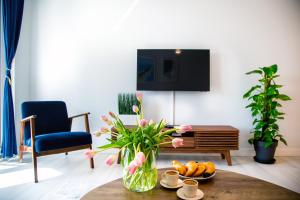 a living room with a table with a vase of flowers at Maya's Flats & Resorts 52 - Aura 40 in Gdańsk