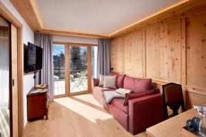 ein Wohnzimmer mit einem roten Sofa und einem TV in der Unterkunft Natur Resort RISSBACHER in Stumm