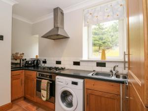 a kitchen with a washing machine and a sink at 1 Station Cottages in Trinafour