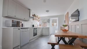 uma cozinha com armários brancos e uma mesa de madeira em Fell Briggs Cottage em Redcar