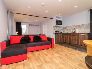 a living room with a red couch and a kitchen at The Lodge in South Molton