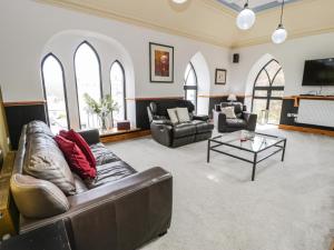 a living room with a leather couch and a table at Greystones Chapel in Caernarfon