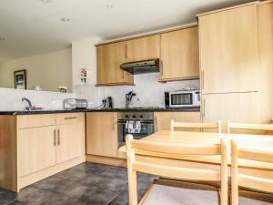 a kitchen with wooden cabinets and a table and chairs at 87 Atlantic Reach in Newquay