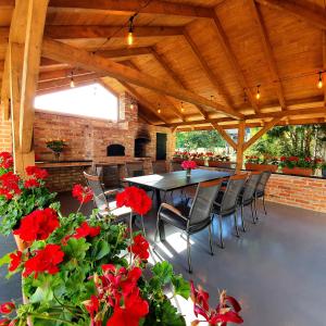 a patio with a table and chairs and red flowers at Leo House in Gaj