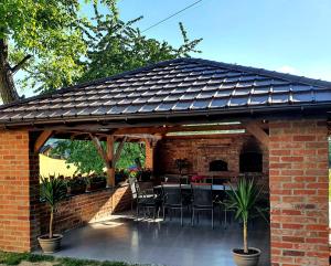 a pavilion with a table and chairs under a roof at Leo House in Gaj