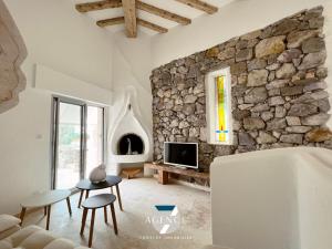 a living room with a stone wall and a tv at Villa IBIZA in Les Issambres