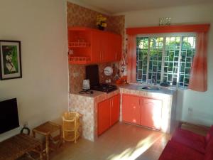 eine kleine Küche mit roten Schränken und einem Fenster in der Unterkunft Ose Cottages in Kisumu