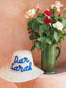 a hat sitting next to a vase with flowers at Dar Sarah-Marrakech, riad authentique idéalement situé. in Marrakesh