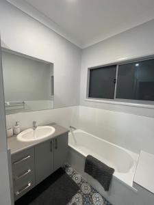ein Badezimmer mit einer Badewanne, einem Waschbecken und einem Spiegel in der Unterkunft Spacious 4 Bedroom House in Townsville