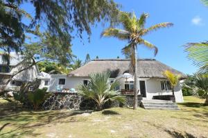 a house with a thatched roof and palm trees at Villa Veloutier Blanc in Blue Bay