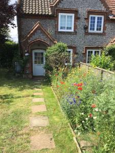 a house with a garden with flowers in front of it at Corner Cottage - base for exploring North Norfolk in Bodham