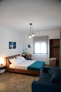 ein Schlafzimmer mit einem großen Bett und einem blauen Sofa in der Unterkunft BIG BLUE HOTEL in Amaliapoli