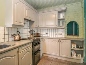 een keuken met witte kasten en een wastafel bij 2 Fleet Street in Castle Douglas