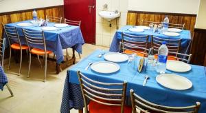 a room with blue tables and chairs with plates and water bottles at Hotel Snow Mountain Mall Road in Manāli
