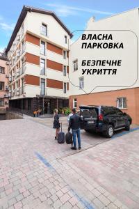um homem e uma mulher com bagagem em frente a um edifício em Etude Hotel em Lviv