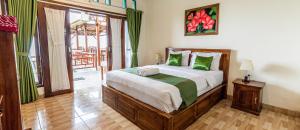 ein Schlafzimmer mit einem Bett mit grünen Kissen in der Unterkunft D' Artha Cottage in Nusa Penida