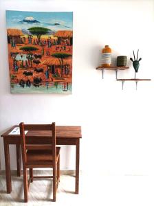 a table and a chair and a painting on the wall at Zanzicrown in Nungwi