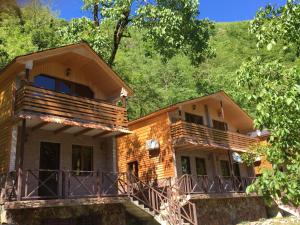 a wooden house with a balcony in the woods at Cottages in mountains in K'veda Bzubzu