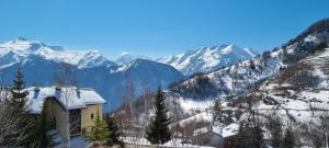 a church on a mountain with snow covered mountains at Studio Uissan pour 5 personnes à côté des pistes in LʼHuez