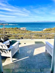 two white benches sitting on a patio looking at the ocean at 11 WESTCLIFF RENTALS in Hermanus