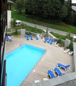 uma piscina com espreguiçadeiras azuis e um monte de móveis em Appartement 2 pièces Résidence les Fermes Emiguy Les Gets em Les Gets