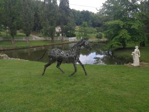 une statue d'une girafe marchant dans l'herbe dans l'établissement Gîte le jardin d eau, à Lamothe-Montravel