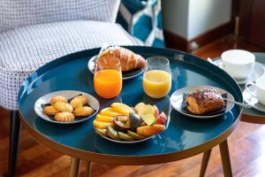 a blue table with plates of breakfast foods and glasses of orange juice at Pavean Suites in Frattaminore