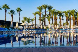 - une piscine bordée de palmiers et de parasols dans l'établissement AQI Pegasos World, à Sidé